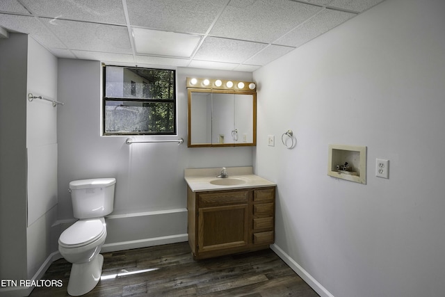 bathroom with hardwood / wood-style flooring, vanity, a drop ceiling, and toilet