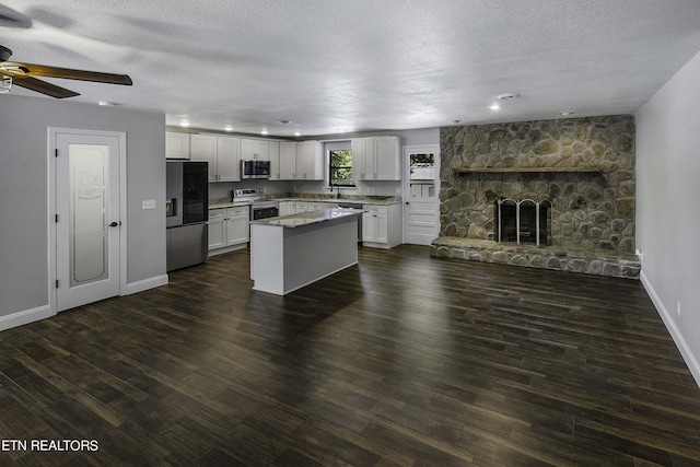 kitchen with a fireplace, a center island, white cabinetry, and stainless steel appliances