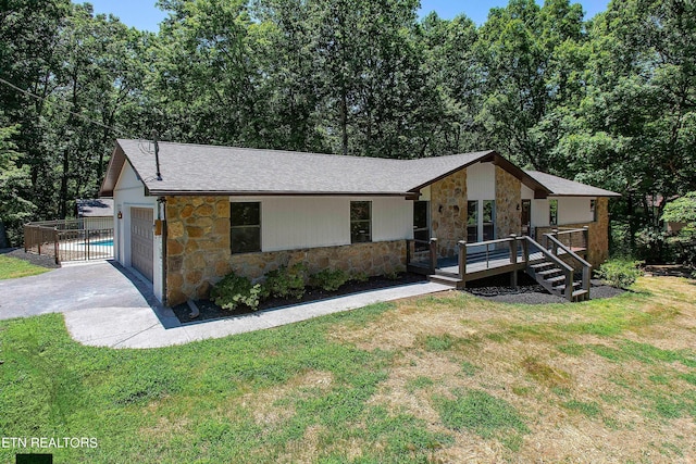 view of front of home featuring a front yard, a garage, and a wooden deck