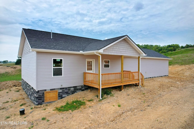 back of house featuring roof with shingles