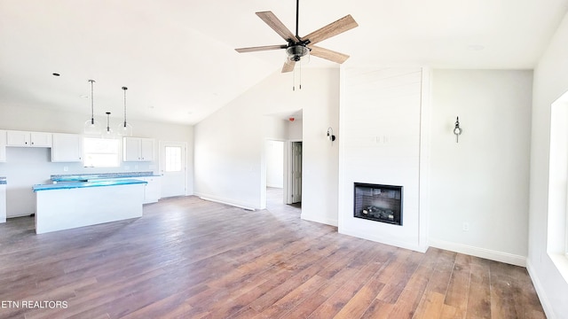 kitchen featuring light hardwood / wood-style floors, white cabinetry, a kitchen island, a large fireplace, and ceiling fan