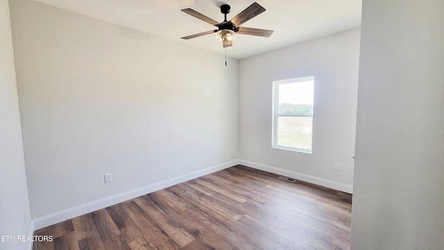 spare room featuring visible vents, dark wood finished floors, baseboards, and ceiling fan