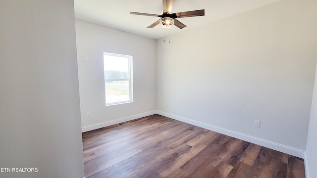 spare room with a ceiling fan, dark wood-style flooring, visible vents, and baseboards