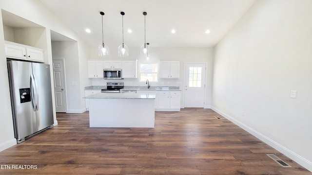 kitchen with vaulted ceiling, stainless steel appliances, a sink, and a kitchen island