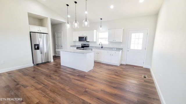 kitchen with dark wood-style flooring, appliances with stainless steel finishes, white cabinets, a sink, and a kitchen island