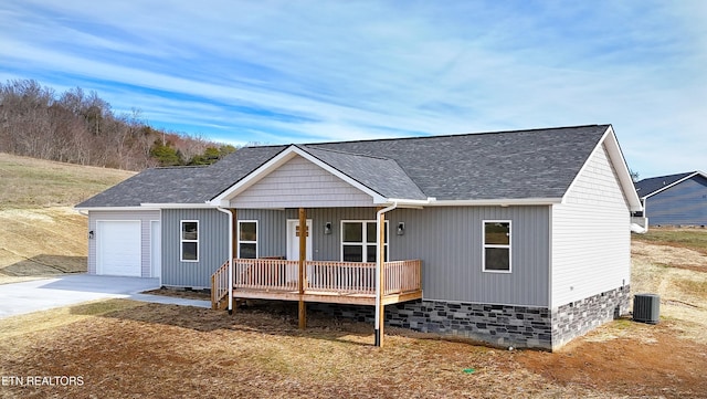 view of front of home featuring driveway, roof with shingles, an attached garage, a porch, and central AC