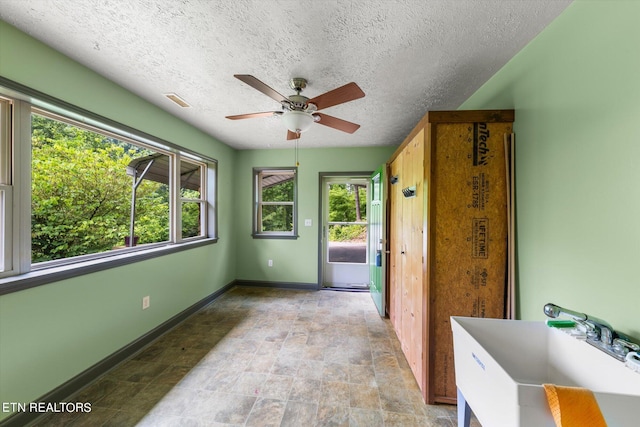 interior space with a textured ceiling, ceiling fan, plenty of natural light, and sink