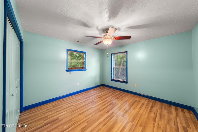 empty room with ceiling fan, a textured ceiling, and light hardwood / wood-style flooring