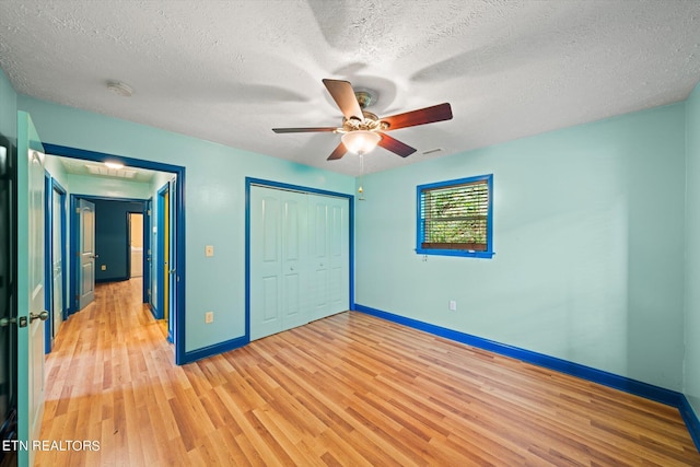 unfurnished bedroom featuring a textured ceiling, ceiling fan, a closet, and light hardwood / wood-style flooring