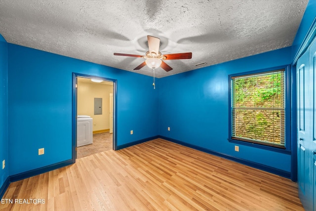 unfurnished bedroom with ceiling fan, electric panel, ensuite bath, light hardwood / wood-style floors, and a textured ceiling