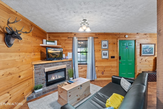 living room with wooden walls, a fireplace, and a textured ceiling