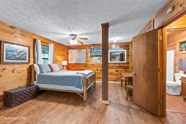 bedroom featuring light wood-type flooring, ceiling fan, and wooden walls