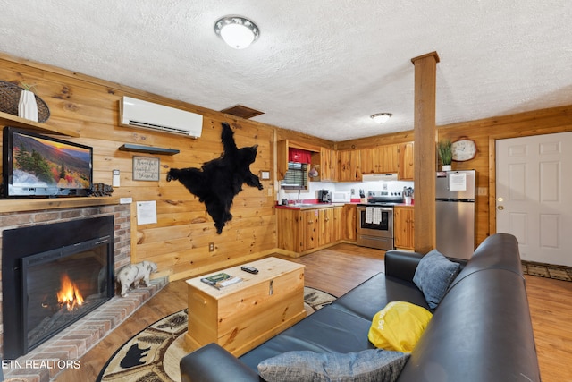 living room featuring wood walls, light wood-type flooring, an AC wall unit, and a textured ceiling