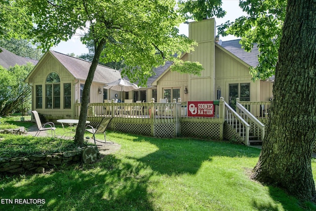 rear view of property featuring a lawn and a wooden deck