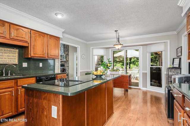 kitchen featuring sink, a center island, hanging light fixtures, crown molding, and black appliances