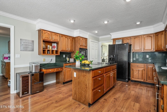 kitchen featuring a center island, backsplash, a textured ceiling, black appliances, and ornamental molding