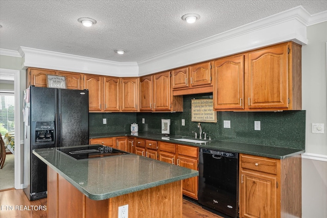 kitchen with black appliances, a kitchen island, crown molding, and sink