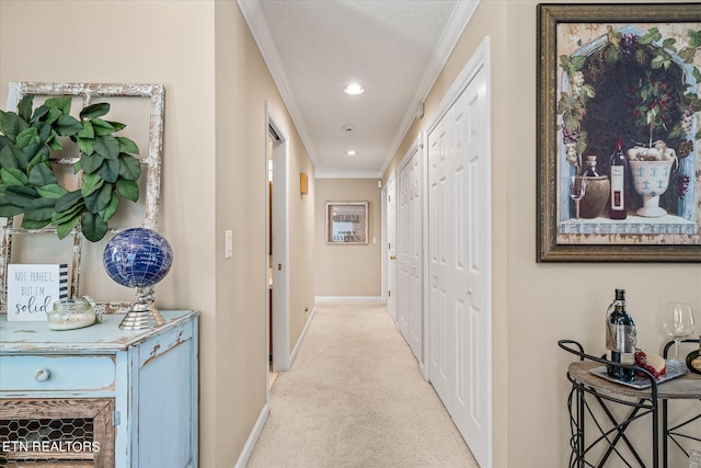 hall with a textured ceiling, light colored carpet, and crown molding