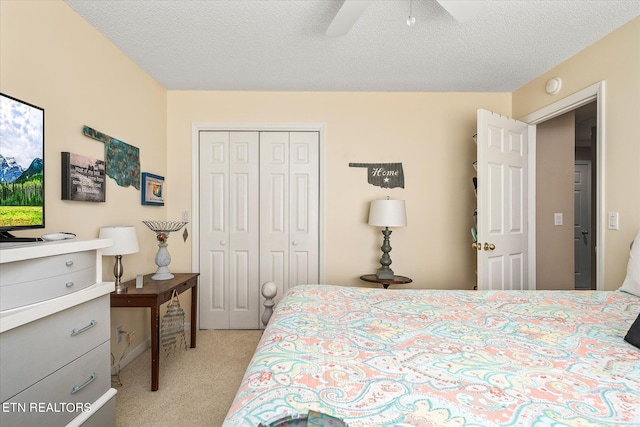 bedroom with ceiling fan, light colored carpet, a textured ceiling, and a closet