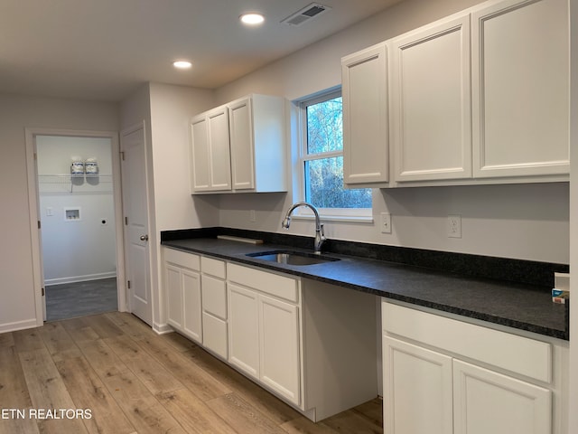 kitchen with white cabinets, light hardwood / wood-style flooring, and sink