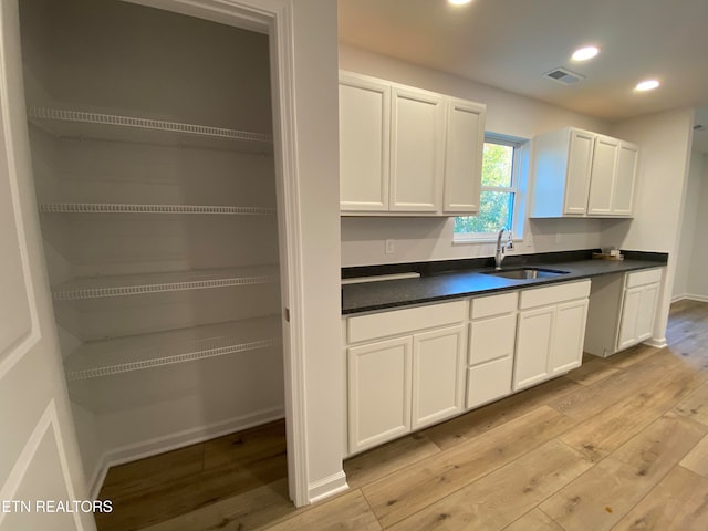 kitchen with sink, white cabinets, and light hardwood / wood-style flooring