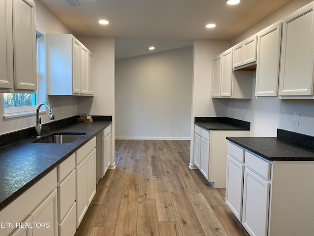 kitchen featuring white cabinets, light wood-type flooring, and sink