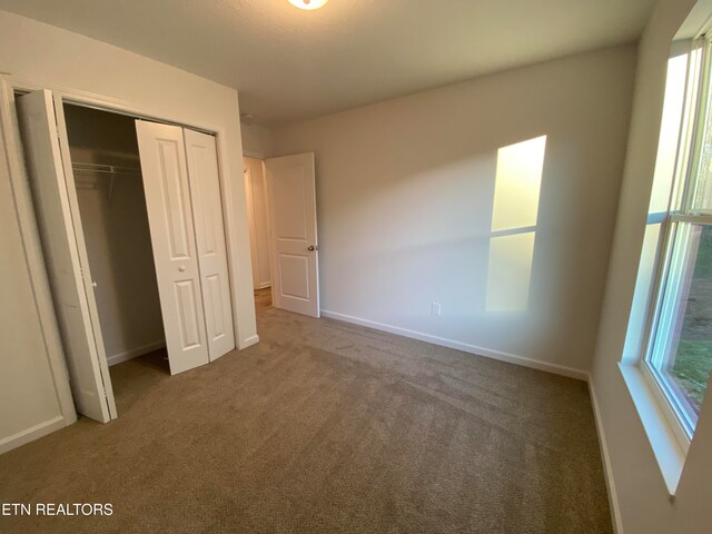 unfurnished bedroom featuring a closet and dark carpet