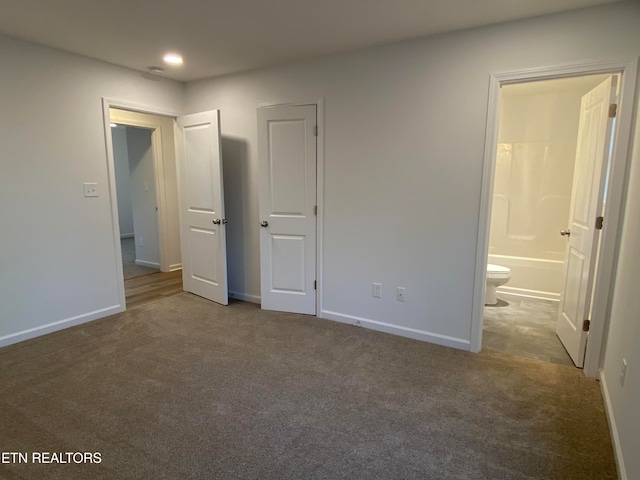 unfurnished bedroom with ensuite bath and carpet flooring