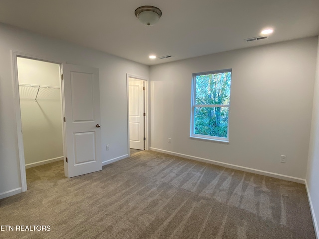 unfurnished bedroom with a walk in closet, carpet flooring, and a closet