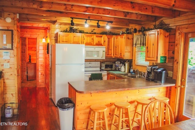 kitchen with sink, white appliances, kitchen peninsula, and beam ceiling