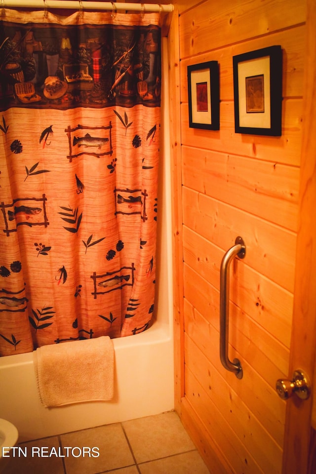 bathroom with wood walls, shower / tub combo with curtain, and tile patterned flooring