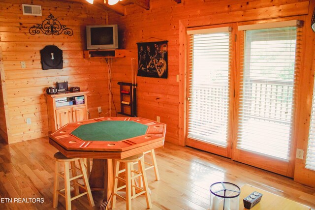 recreation room with light hardwood / wood-style flooring and wooden walls