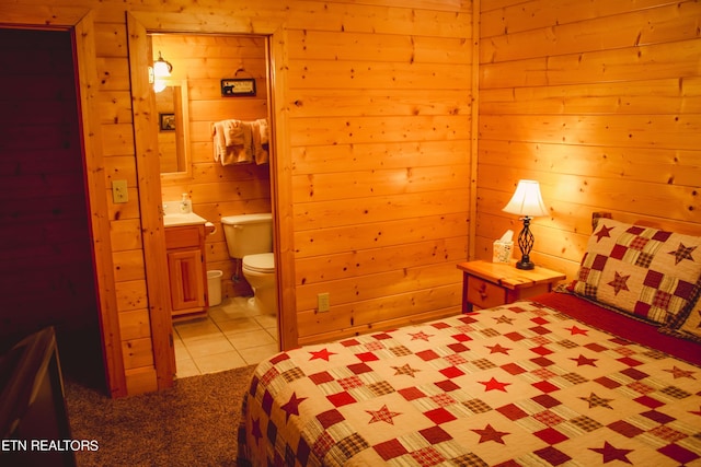 bedroom with wood walls, ensuite bath, and light tile patterned flooring