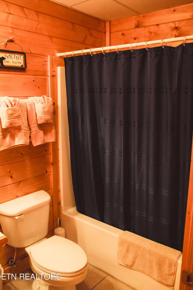 bathroom with toilet, tile patterned flooring, and wood walls