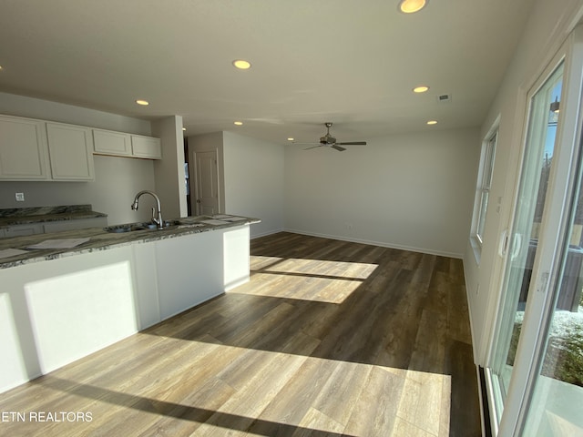 kitchen with sink, hardwood / wood-style flooring, ceiling fan, stone countertops, and white cabinetry