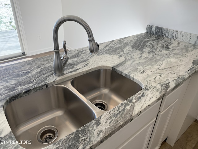 interior details featuring white cabinets, stone countertops, and sink