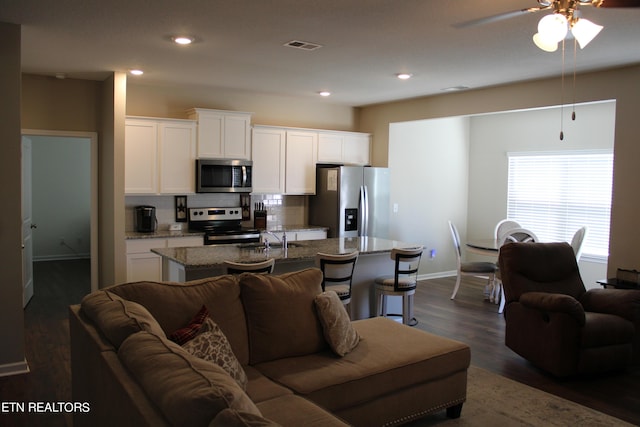 living room featuring dark wood-type flooring, sink, and ceiling fan