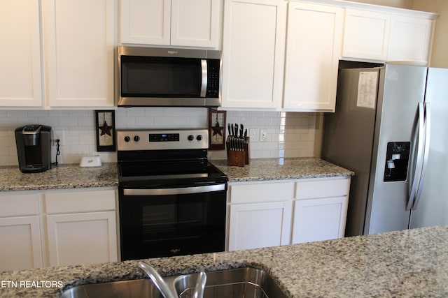 kitchen featuring decorative backsplash, light stone counters, white cabinetry, and stainless steel appliances