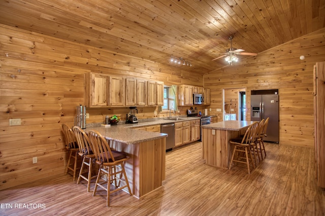 kitchen with stainless steel appliances, vaulted ceiling, light stone counters, a kitchen bar, and light wood-type flooring