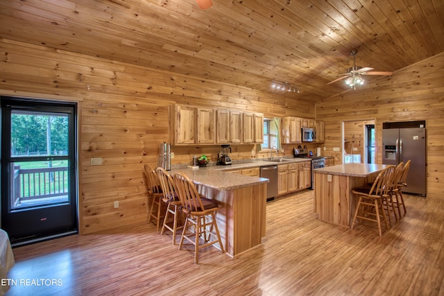 kitchen with vaulted ceiling, stainless steel appliances, kitchen peninsula, a kitchen bar, and sink