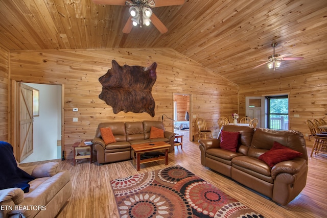 living room featuring lofted ceiling, ceiling fan, light wood-type flooring, wood walls, and wood ceiling