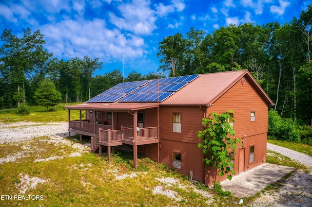 rear view of house with solar panels, a porch, and a garage