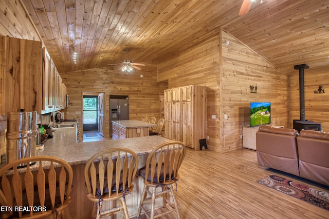 kitchen featuring wood ceiling, vaulted ceiling, kitchen peninsula, wooden walls, and a wood stove