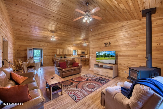 living room with wood ceiling, ceiling fan, light hardwood / wood-style flooring, and a wood stove