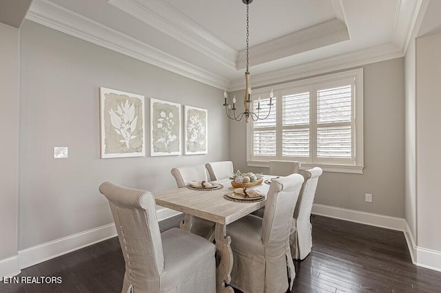 dining area featuring dark wood-type flooring, crown molding, a raised ceiling, and a notable chandelier