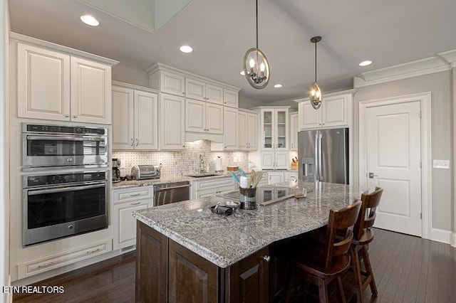 kitchen with light stone counters, white cabinets, a center island, and stainless steel appliances