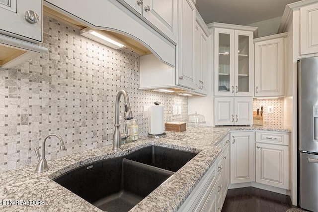 kitchen with stainless steel refrigerator with ice dispenser, white cabinetry, tasteful backsplash, and light stone countertops