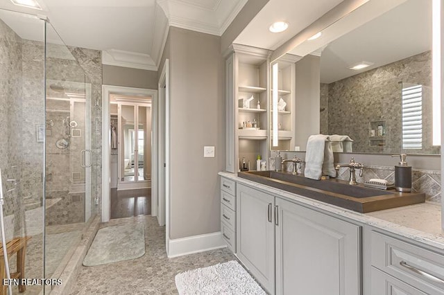 bathroom featuring a shower with shower door, vanity, and ornamental molding