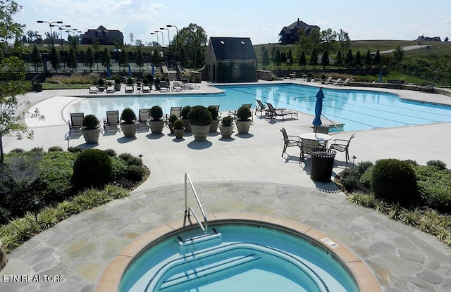 view of swimming pool with a patio area and a hot tub