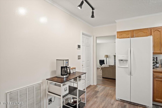 kitchen with light hardwood / wood-style floors, track lighting, white fridge with ice dispenser, a textured ceiling, and crown molding